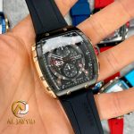 A hand holding a CURREN 8442 chronograph watch with a black silicone band and a black and rose gold case.