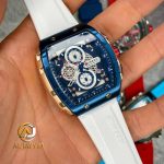 A hand holding the CURREN 8442 multi-function chronograph watch, showing its blue and rose gold case and white silicone band.