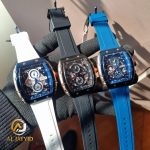 A gloved hand holding three CURREN 8442 chronograph sports watches with silicone bands in white, black, and blue colors.