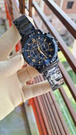 A gloved hand holding the black and gold POEDAGAR 973 luxury sports watch for men, showing the detailed dial and metal band.