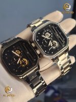 A gloved hand holding two Poedagar 628 minimalist wristwatches, one in black with gold accents and one in silver.