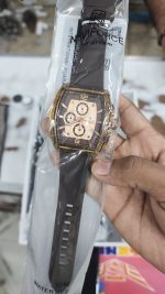 A Naviforce NF6101 men's watch in Rose Gold Coffee held in a hand, still inside its transparent retail packaging.