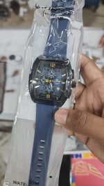 A hand holding the Naviforce NF6101 men's watch, which has a blue strap and dial, inside its clear packaging.