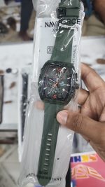 A person holding the Naviforce 6101 Men's Watch in green, shown in its original transparent packaging.