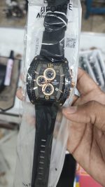 A Naviforce NF6101 men's watch with a black case, rose gold details, and a black strap, shown inside its plastic packaging.