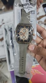 A person holding a new Naviforce NF6101 men's watch in rose gray, still in its clear packaging.