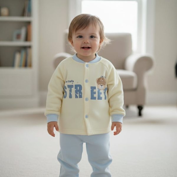A smiling toddler stands in a living room wearing a cream and light blue Baby Cartoon Velvet Thermal Base Layer Set.