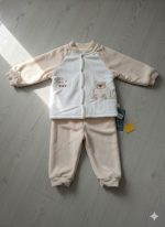 A soft, two-piece baby cartoon velvet thermal base layer set in cream and beige, laid flat on a wooden surface.