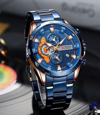 A front-angle view of the Curren 8402 Blue Watch, featuring a blue dial with orange accents and a two-tone blue and rose gold case.