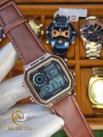 A gloved hand holding a Casio AE-1200WHL-5AV men's watch. The watch has a rose gold case and a brown leather strap.