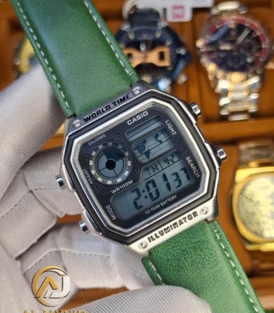 A person wearing a white glove holding a Casio AE-1200WHL-5AV men's watch with a distinctive green leather strap.