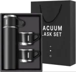 A black vacuum flask set displayed in a presentation box, including a tall flask and two matching cups with silver details.
