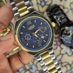 A close-up, top-down shot of a gold-toned LIGE luxury chronograph watch being held by a hand