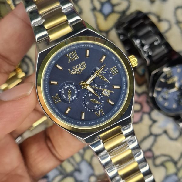 A close-up, top-down shot of a gold-toned LIGE luxury chronograph watch being held by a hand