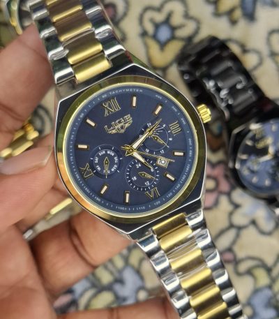 A close-up, top-down shot of a gold-toned LIGE luxury chronograph watch being held by a hand