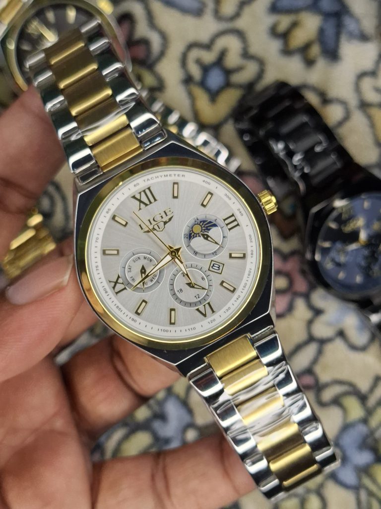 A close-up, top-down shot of a gold-toned LIGE luxury chronograph watch being held by a hand