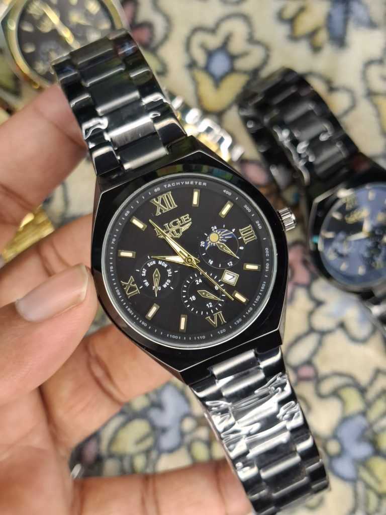 A close-up, top-down shot of a gold-toned LIGE luxury chronograph watch being held by a hand