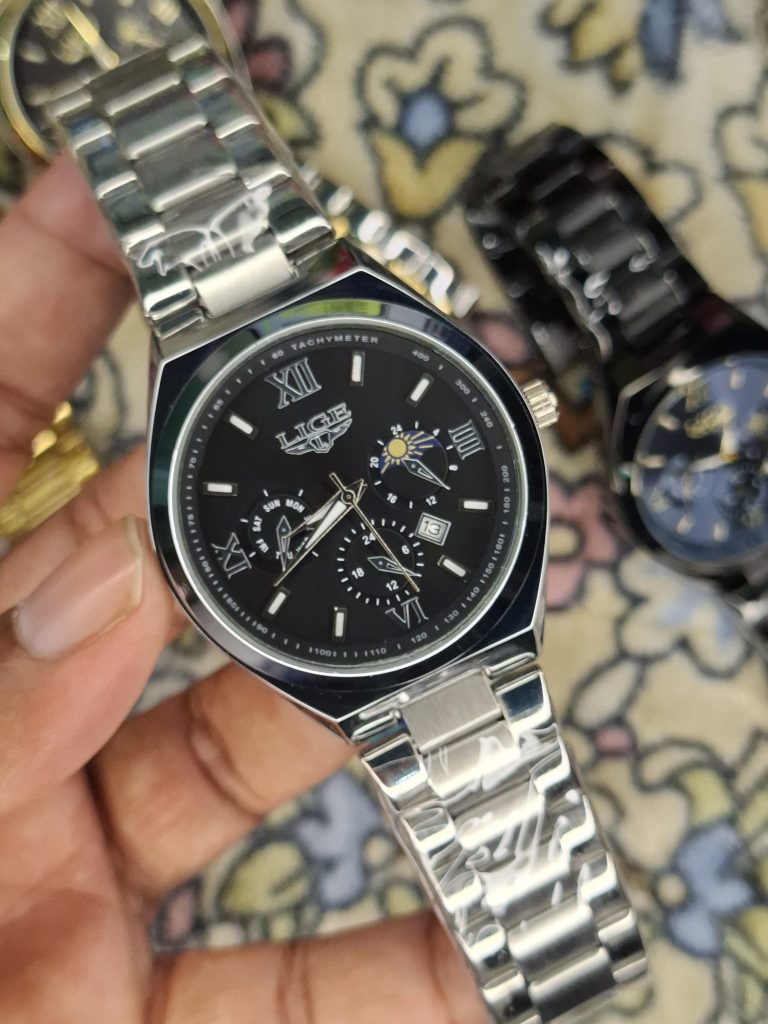 A close-up, top-down shot of a gold-toned LIGE luxury chronograph watch being held by a hand