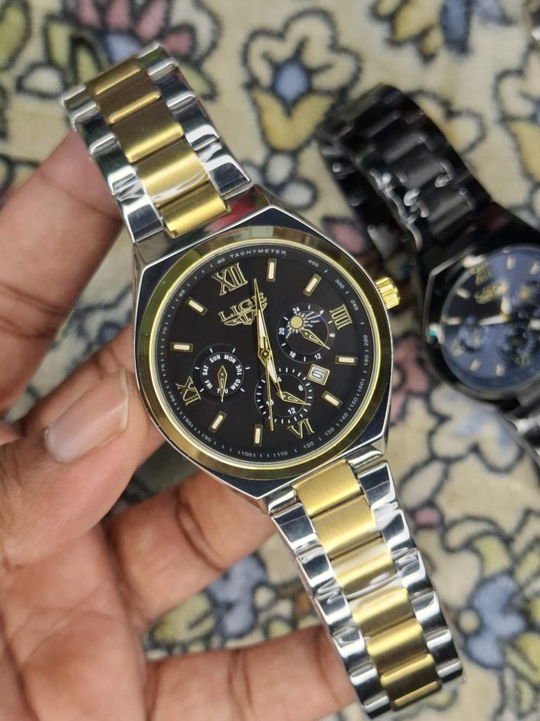 A close-up, top-down shot of a gold-toned LIGE luxury chronograph watch being held by a hand