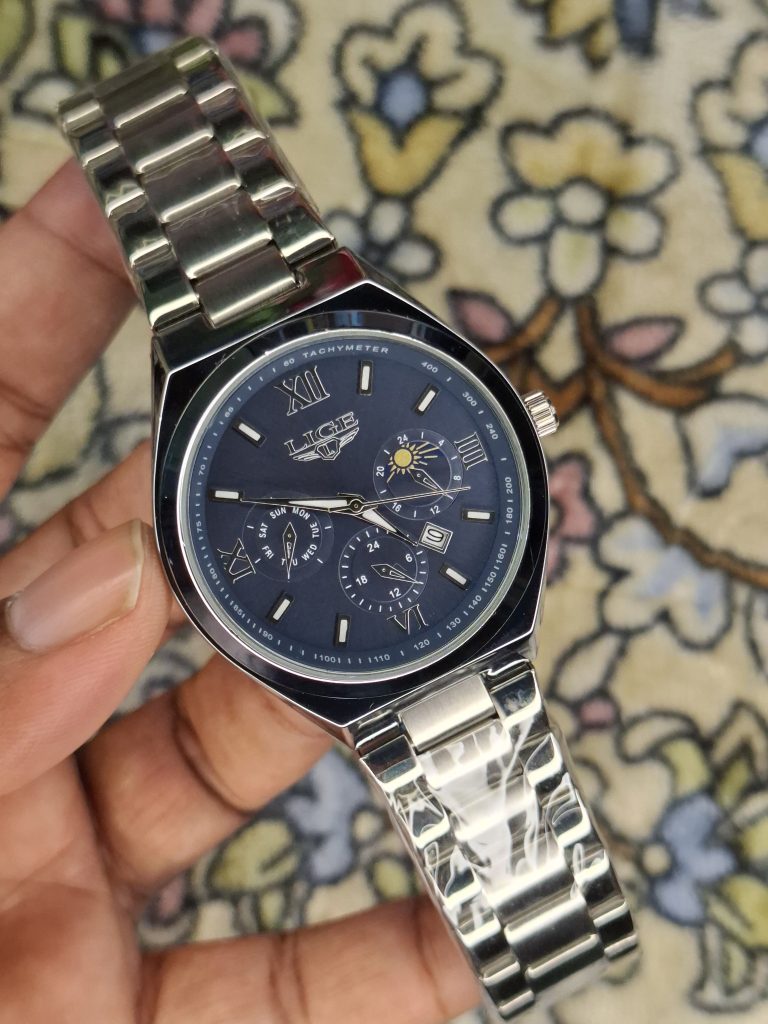 A close-up, top-down shot of a gold-toned LIGE luxury chronograph watch being held by a hand
