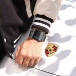 A black Poedagar 857 men's wristwatch with a rectangular case and a unique rotating dial display, resting on a white cushion inside a watch box.